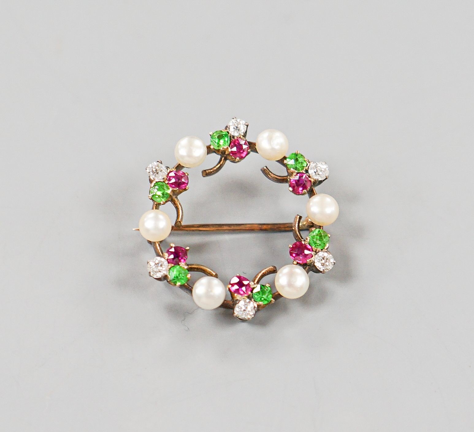 An early 20th century yellow metal, cultured pearl, ruby, garnet and diamond set openwork circular brooch, 25mm, gross weight 4.9 grams.